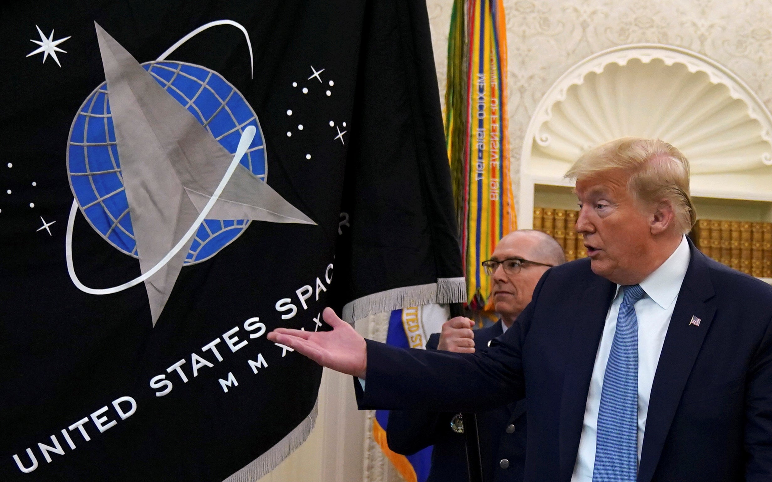 President Donald Trump gestures towards the U.S. Space Force flag during a presentation of the flag in the Oval Office of the White House in Washington, U.S., May 15, 2020
