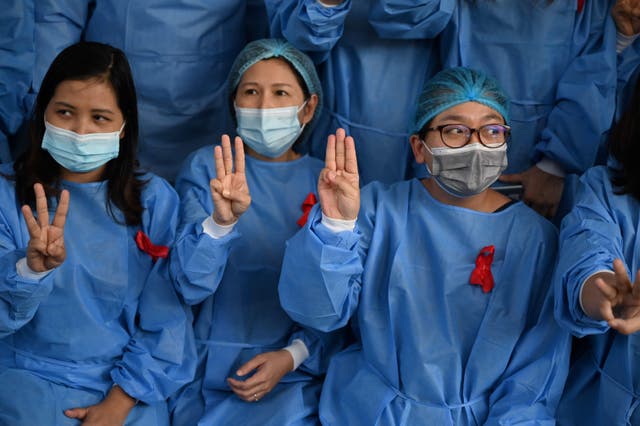 <p>Medical staff make a three finger salute with red ribbons on their uniform at the Yangon General Hospital in Yangon on February 3, 2021 as calls for a civil disobedience gather pace following a military coup detaining civilian leader Aung San Suu Kyi</p>