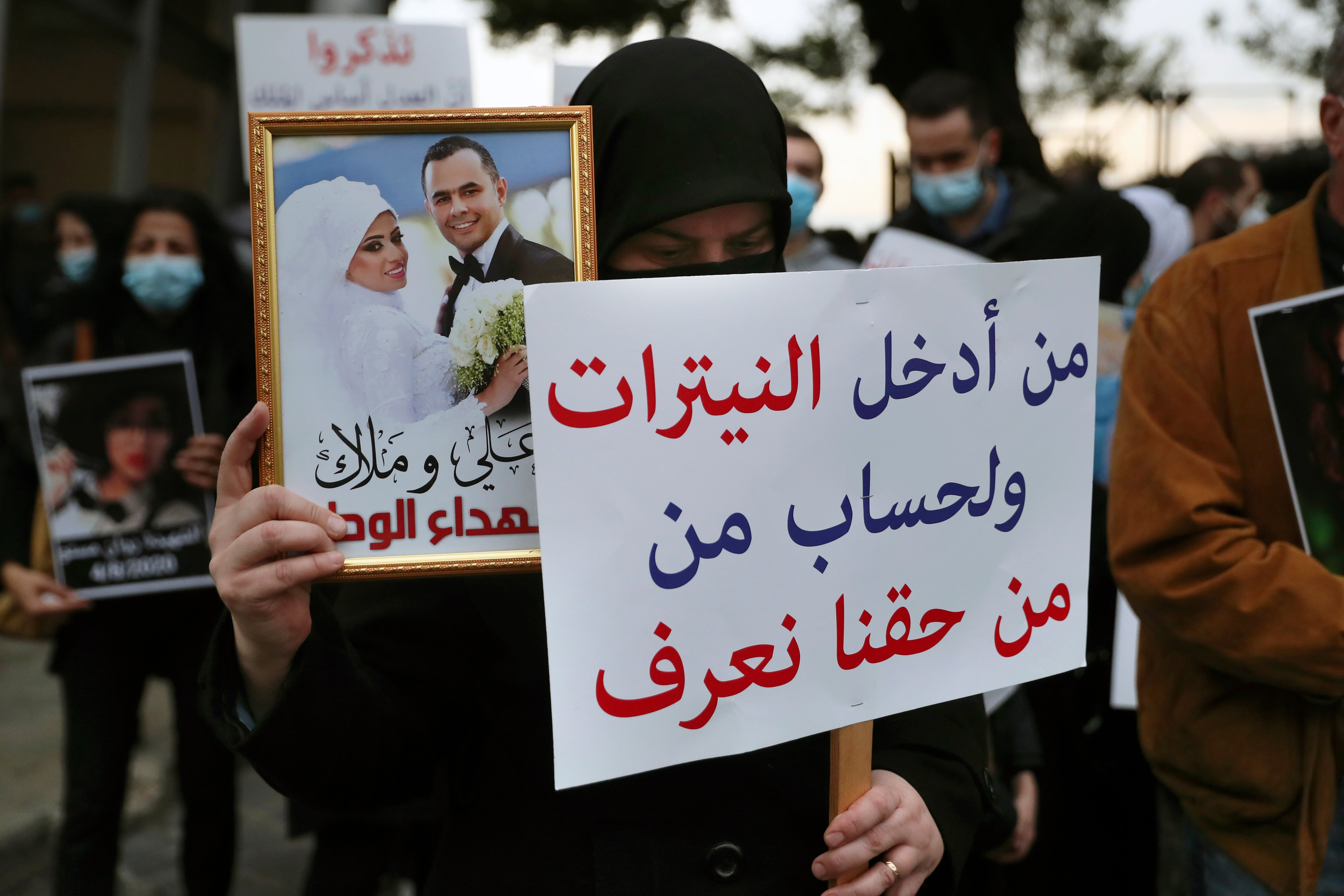 Relatives in Beirut hold portraits of the victims six months on from the blast