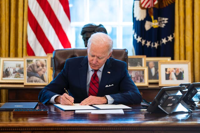 <p>Joe Biden signs an executive order in the Oval Office</p>