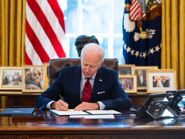 <p>Joe Biden signs an executive order in the Oval Office</p>