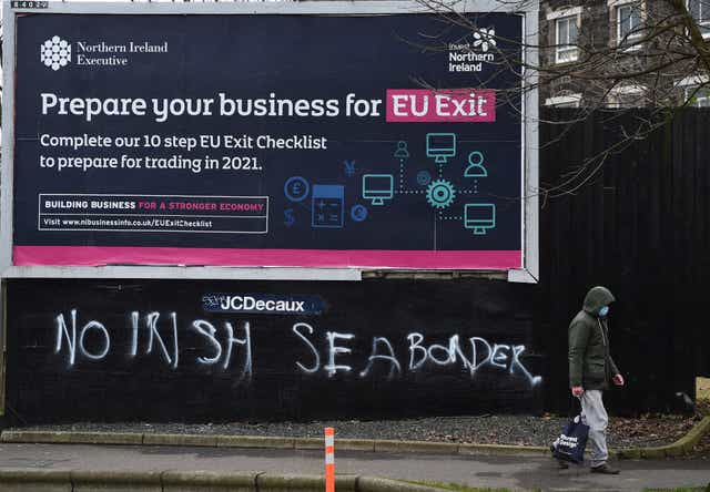  A man walks past graffiti in the loyalist Sandy row area, which reads ‘No Irish sea border’ under an EU Exit billboard on 30 January, 2021 in Belfast. The Police Service of Northern Ireland has been monitoring growing unionist discontent regarding the implementation of a so called Irish sea border