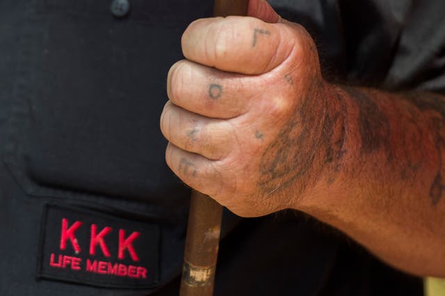 <p>Un miembro del Ku Klux Klan, con la palabra "Amor" tatuada en sus dedos, sostiene una bandera durante un mitin, pidiendo la protección de los monumentos confederados del sur, en Charlottesville, Virginia, el 8 de julio de 2017. - El mitin de la tarde en Esta tranquila ciudad universitaria ha sido autorizada por funcionarios en Virginia y ha provocado un acalorado debate en Estados Unidos, donde los críticos dicen que la extrema derecha se ha animado con la elección de Donald Trump a la presidencia. </p>