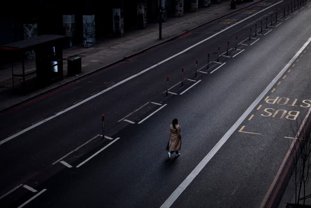 <p>A lone woman walks down the middle of a main road in Westminster during England's third national lockdown to curb the spread of coronavirus</p>