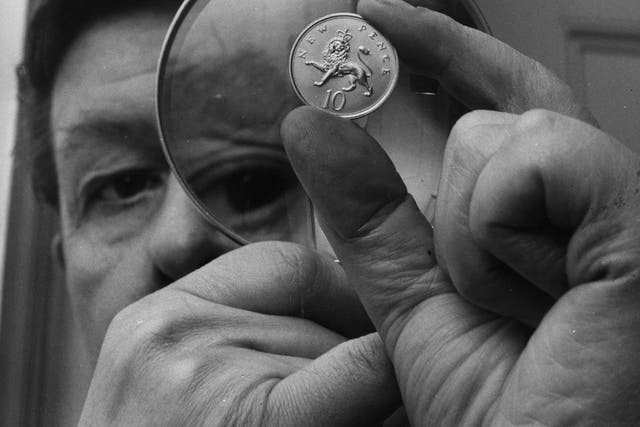 <p>Christopher Ironside, designer of the reverse side of the decimal 10 pence piece, examines the coin through a magnifying glass at the Royal Mint in 1968</p>