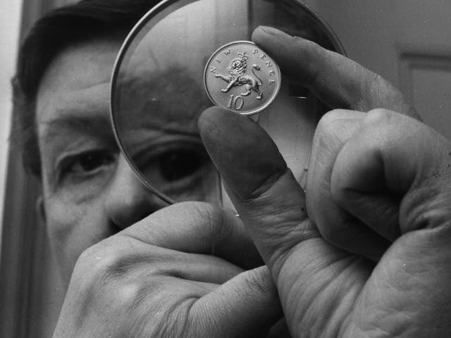 <p>Christopher Ironside, designer of the reverse side of the decimal 10 pence piece, examines the coin through a magnifying glass at the Royal Mint in 1968</p>