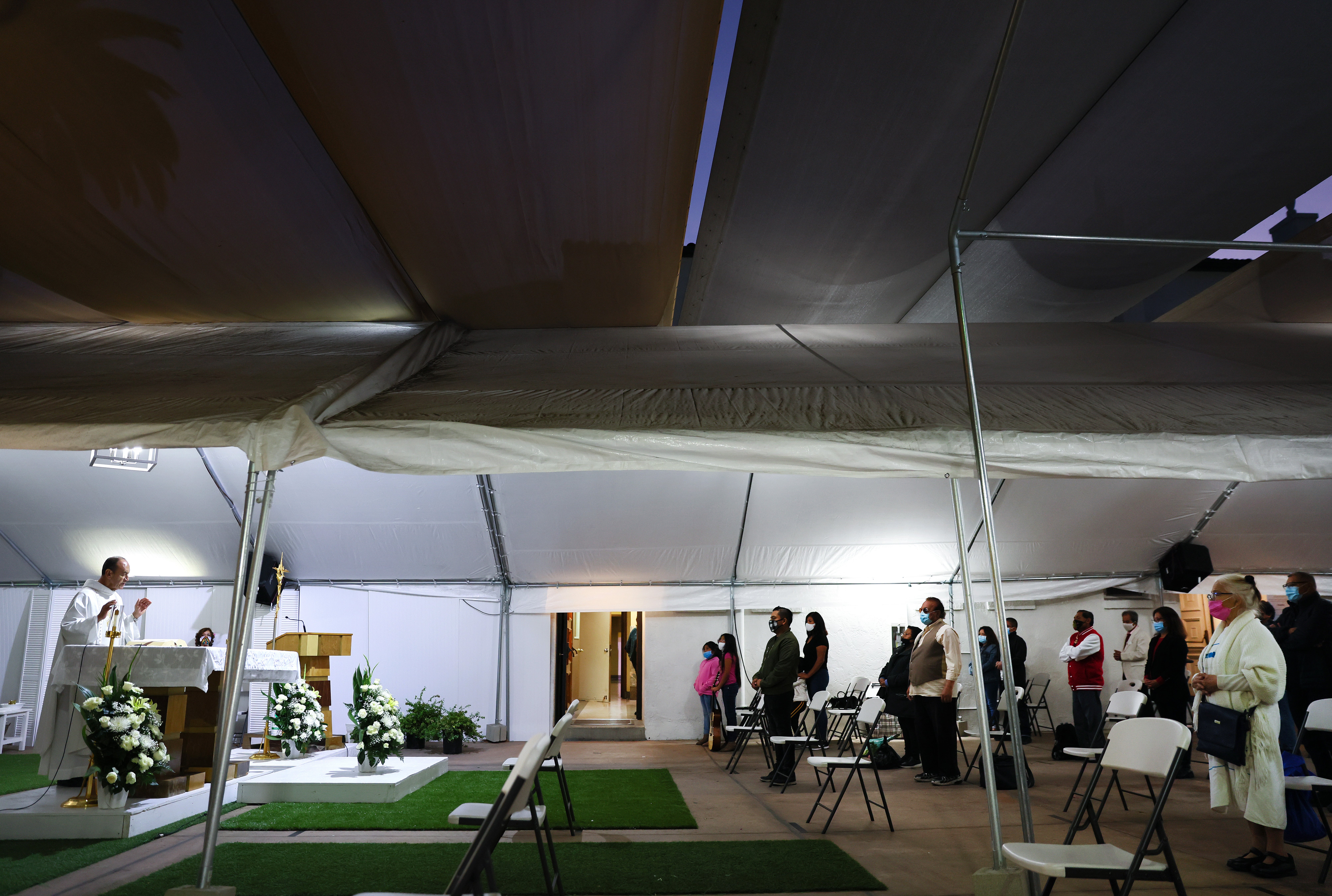 <p>LOS ANGELES, CALIFORNIA - DECEMBER 12: The Rev. Arturo Corral (L) speaks during outdoor Mass marking the Feast of Our Lady of Guadalupe at the historic Our Lady Queen of Angels (La Placita) Church amid the COVID-19 pandemic on December 12, 2020 in Los Angeles, California. Masses were held in the church courtyard beneath tents throughout the day with congregants seated in socially distanced chairs and required to wear face coverings to prevent the spread of the coronavirus. </p>