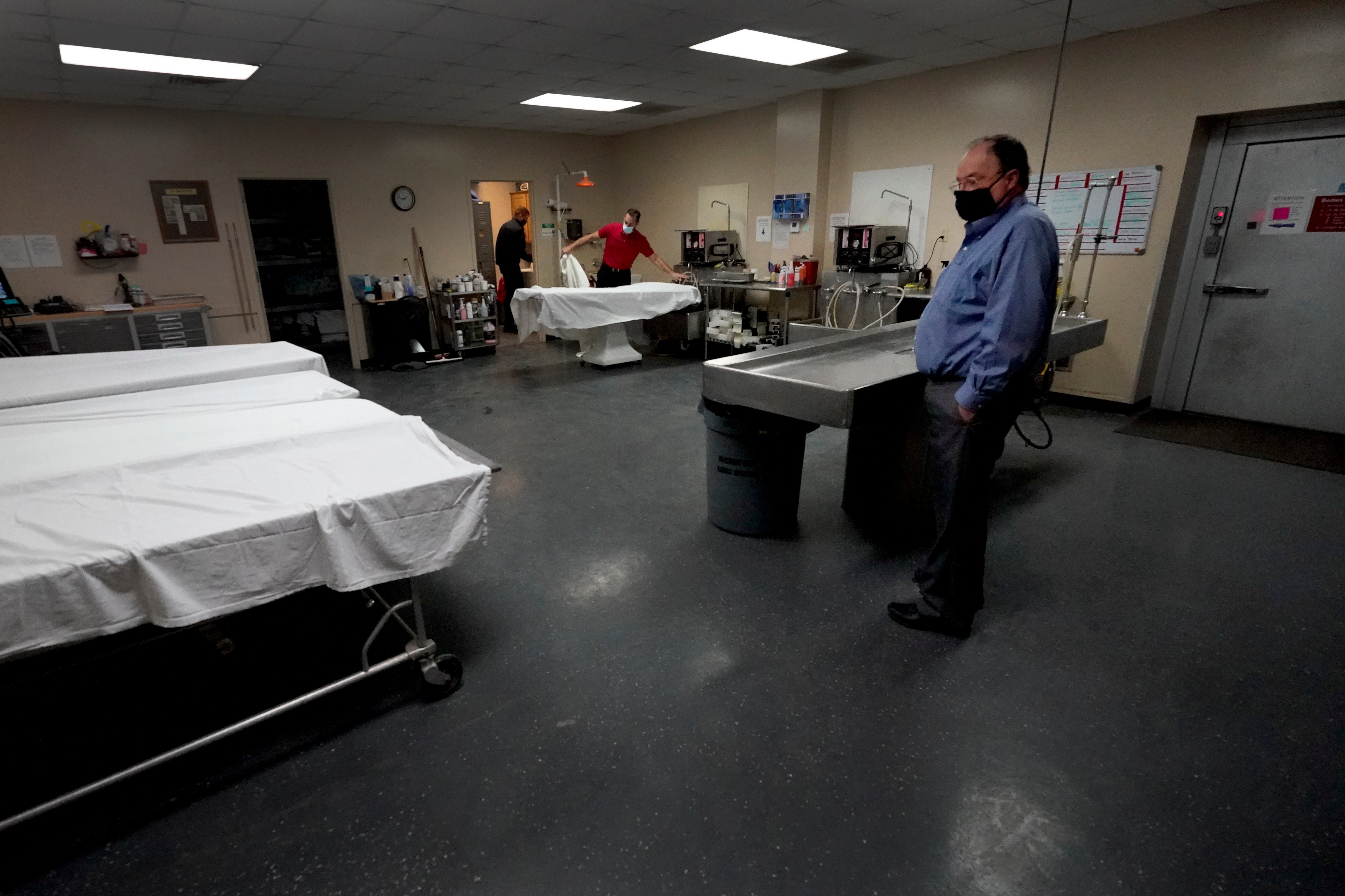 Owner Brian Simmons looks over the preparation room in mortuary as workers get ready to prepare a body Thursday, Jan. 28, 2021, in Springfield, Mo. Simmons has been making more trips to homes to pick up bodies to be cremated and embalmed since the pandemic hit. For many families, home is a better setting than the terrifying scenario of saying farewell to loved ones behind glass or during video calls amid the coronavirus pandemic.