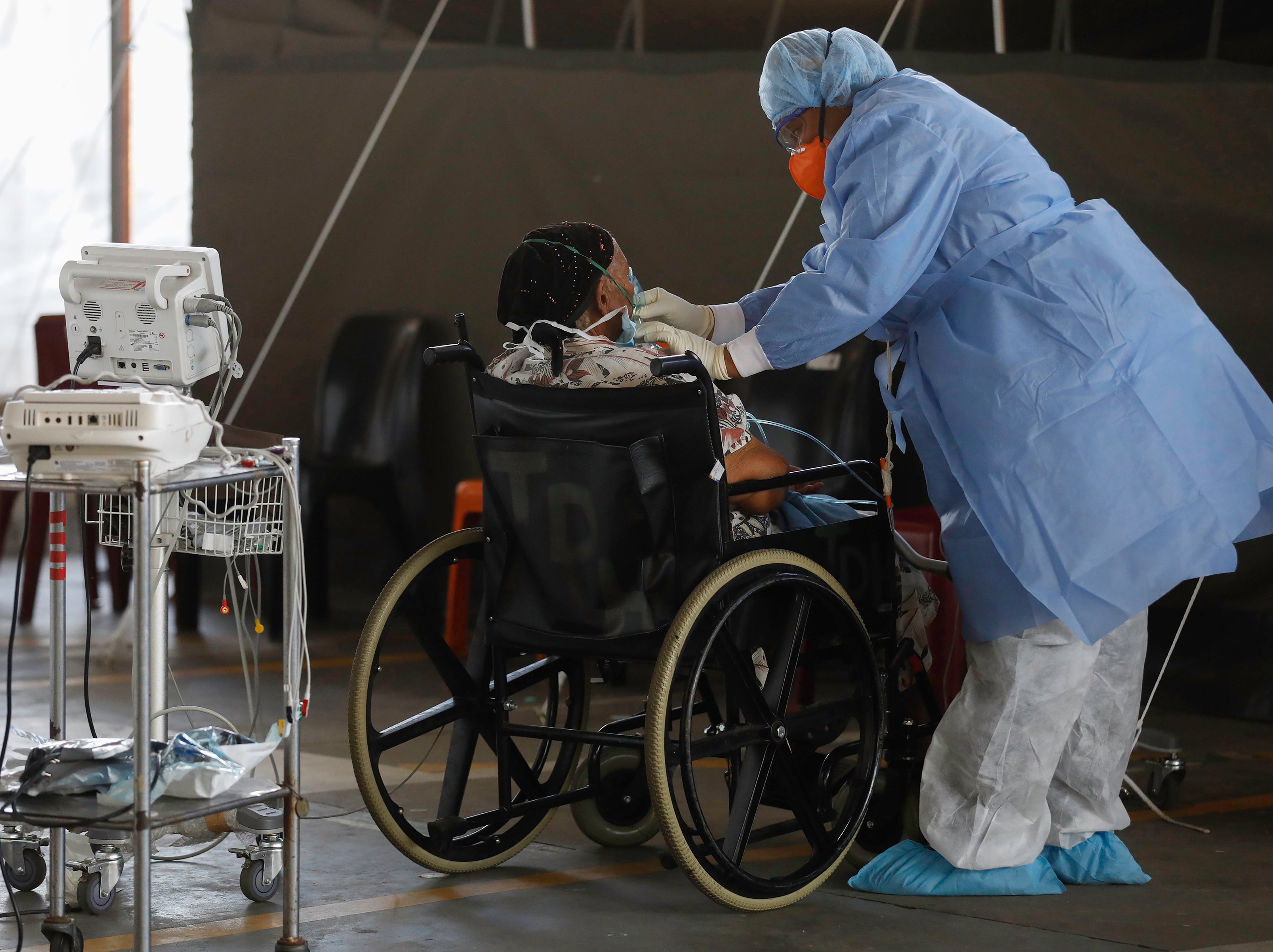 A healthcare worker wearing personal protective equipment (PPE) stands next to a patient at the temporary wards dedicated to the treatment of possible COVID-19 coronavirus patients at Steve Biko Academic Hospital in Pretoria, South Africa, 19 January 2021