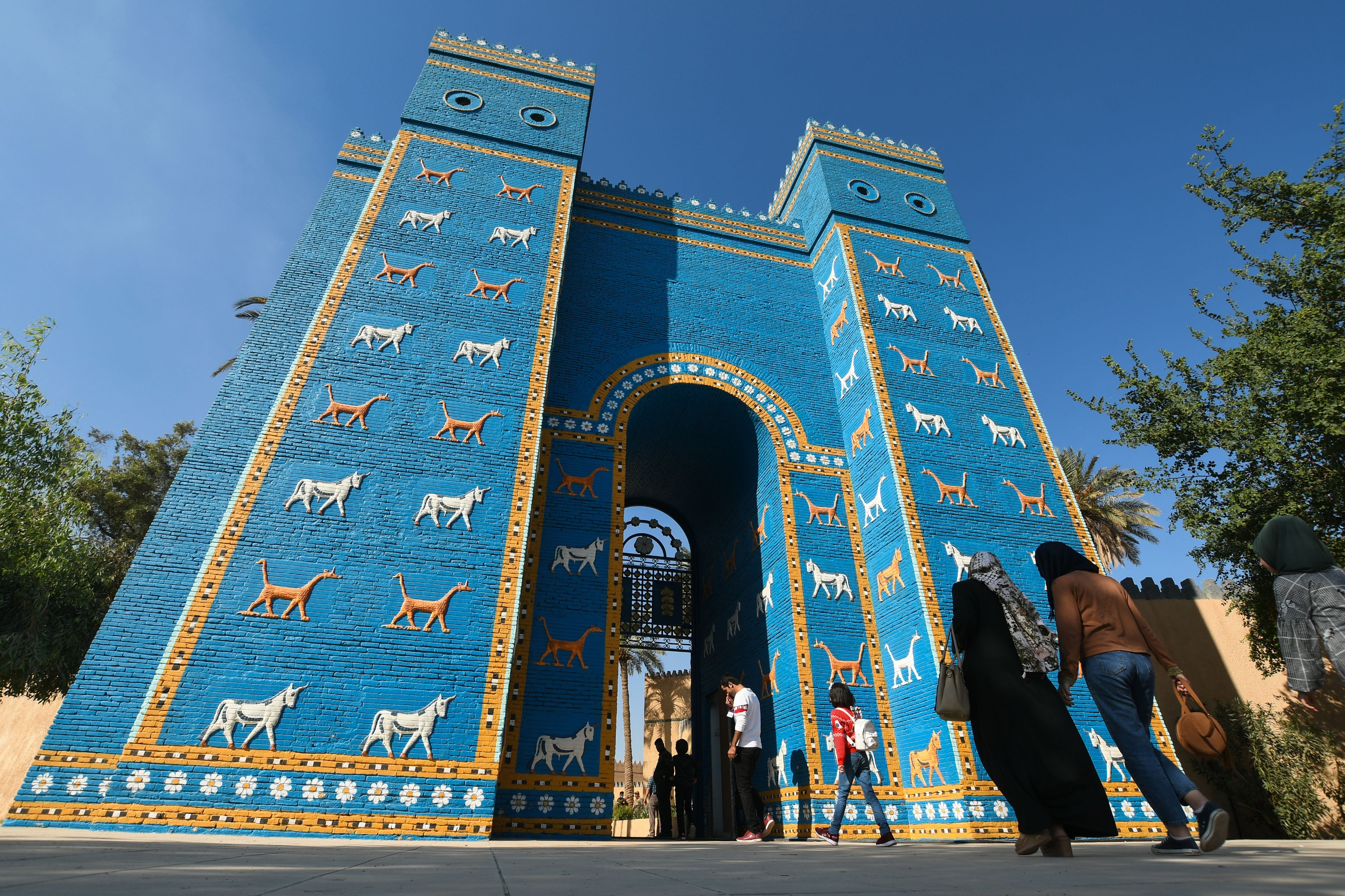 Visitors walk towards a replica of the Gate of Ishtar at the archaeological site of ancient Babylon, about 50 miles south of the Iraqi capital Baghdad, on 14 November 2020