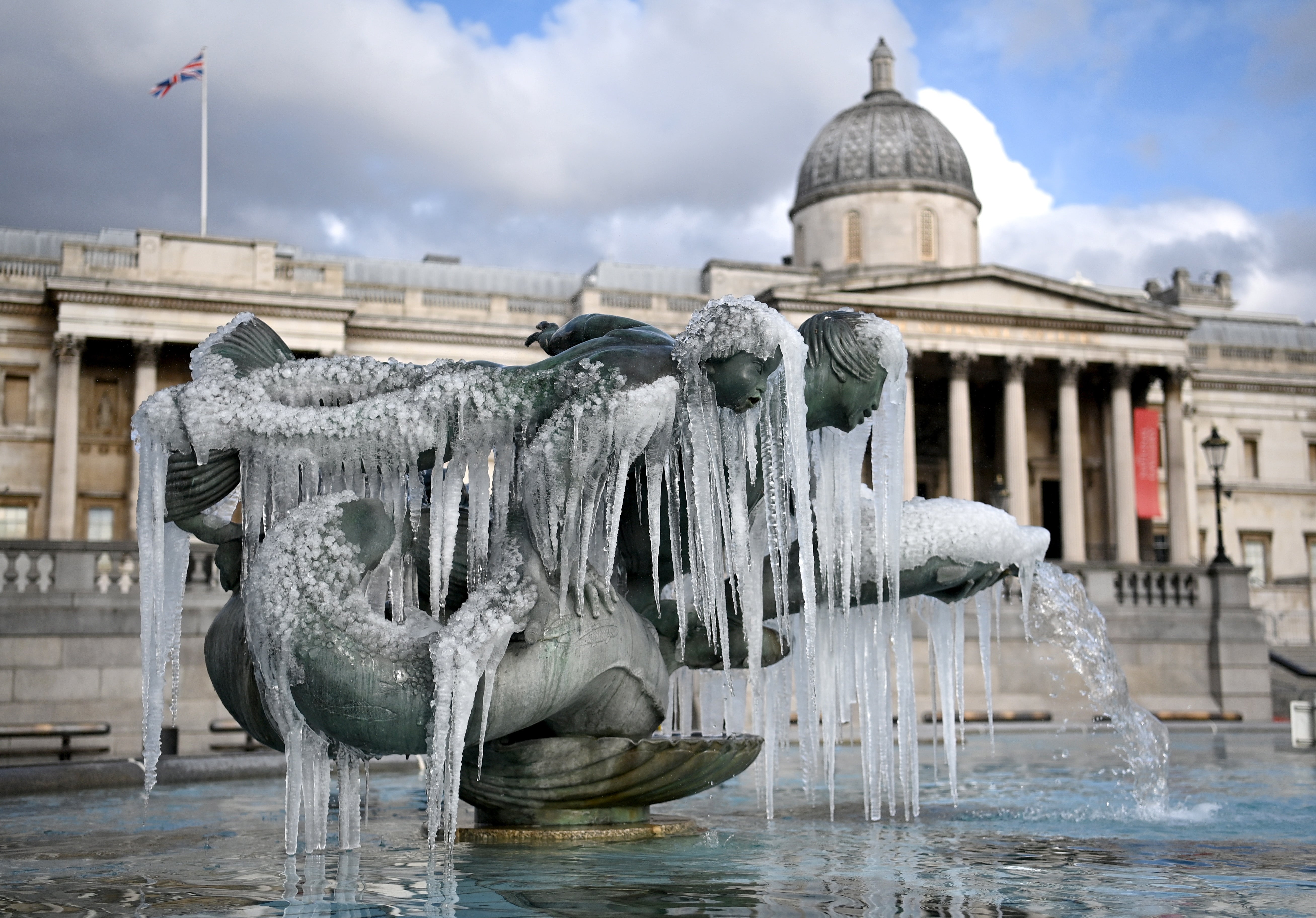 Ice melts in the sunshine after forming on Trafalgar Square’s fountains