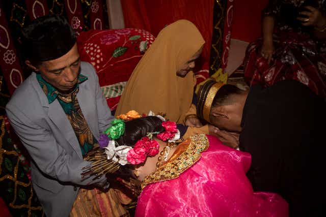 <p>This picture taken on July 25, 2020 shows 18-year-old Lia (C) and her 21-year-old husband Randi (R, not their real names) asking for their parents’ blessing after getting married in the village of Tampapadang in Mamuju, West Sulawesi. </p>