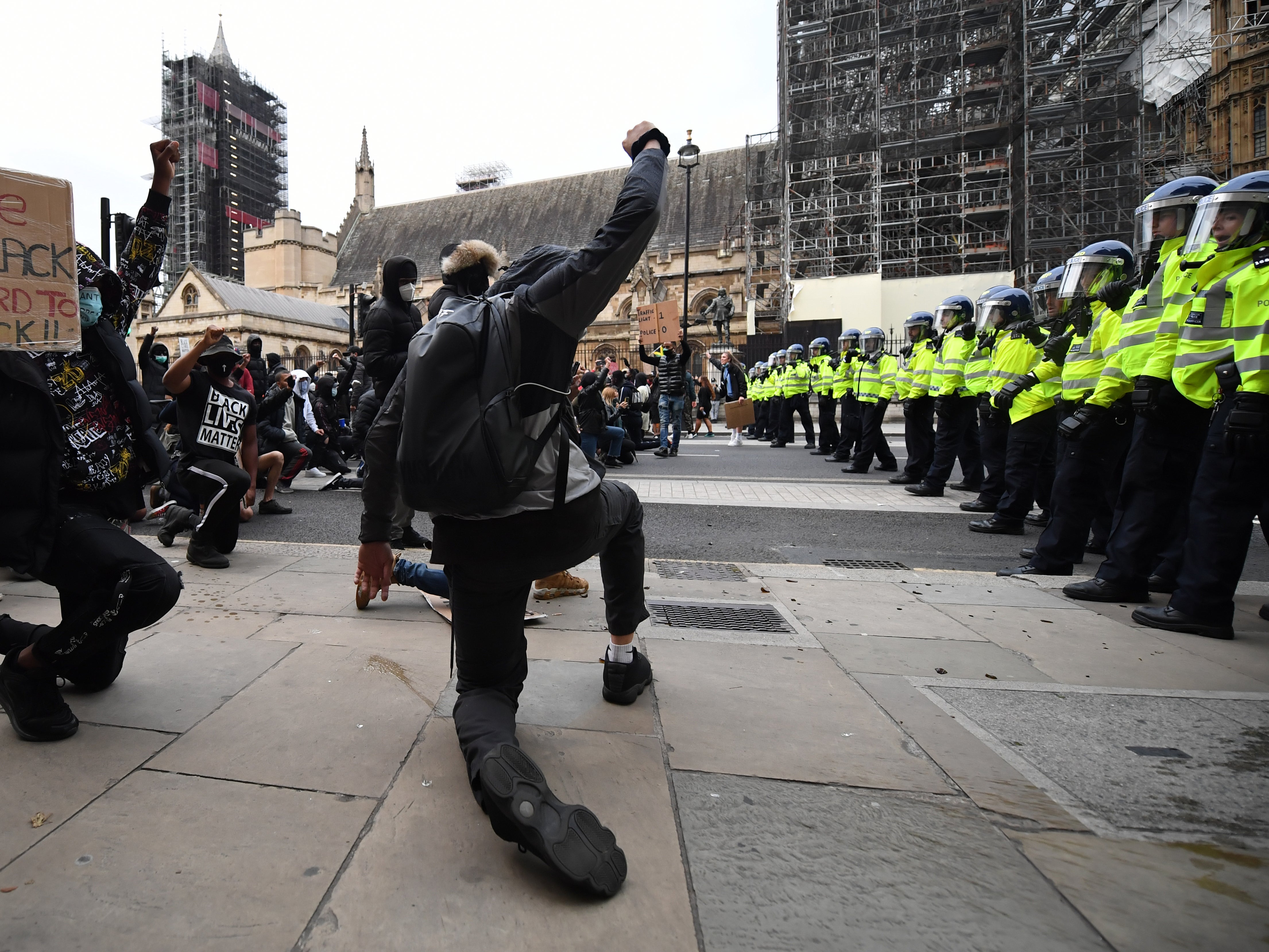 Protesters kneel and raise their fists in the air as police officers line up outside the Houses of Parliament during a protest last summer