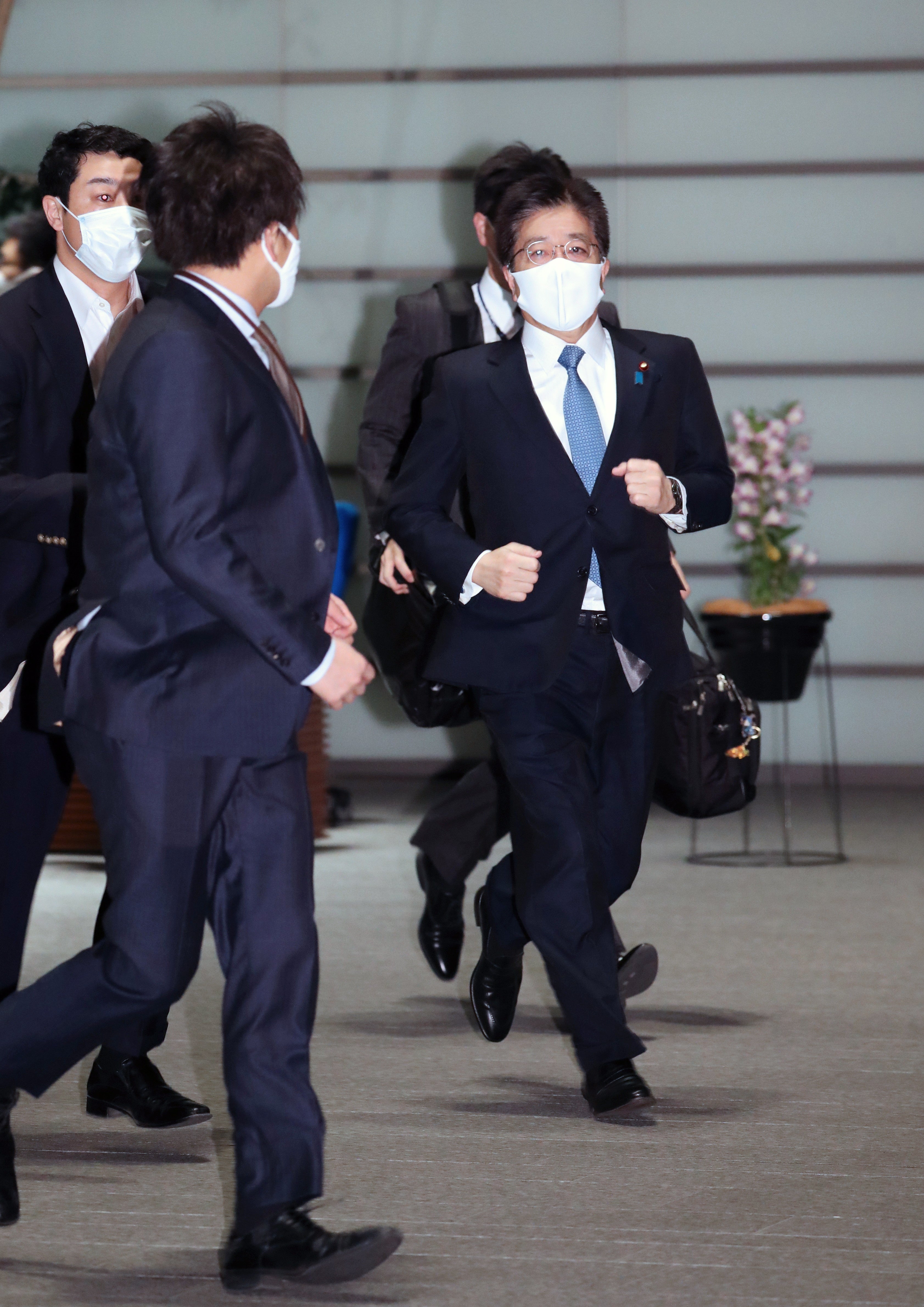 Japanese Chief Cabinet Secretary Katsunobu Kato (R) rushes into the prime minister official residence after a strong earthquake hit northeastern Japan