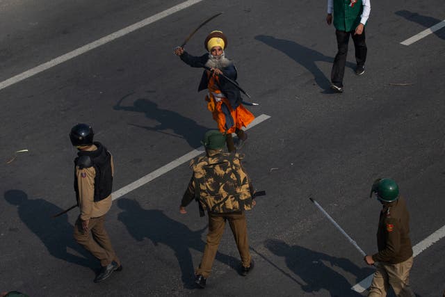 <p>In this January 2021 photo, a Nihang brandishes a sword at policemen as protesting farmers march to the capital breaking police barricades during India's Republic Day celebrations in New Delhi</p>