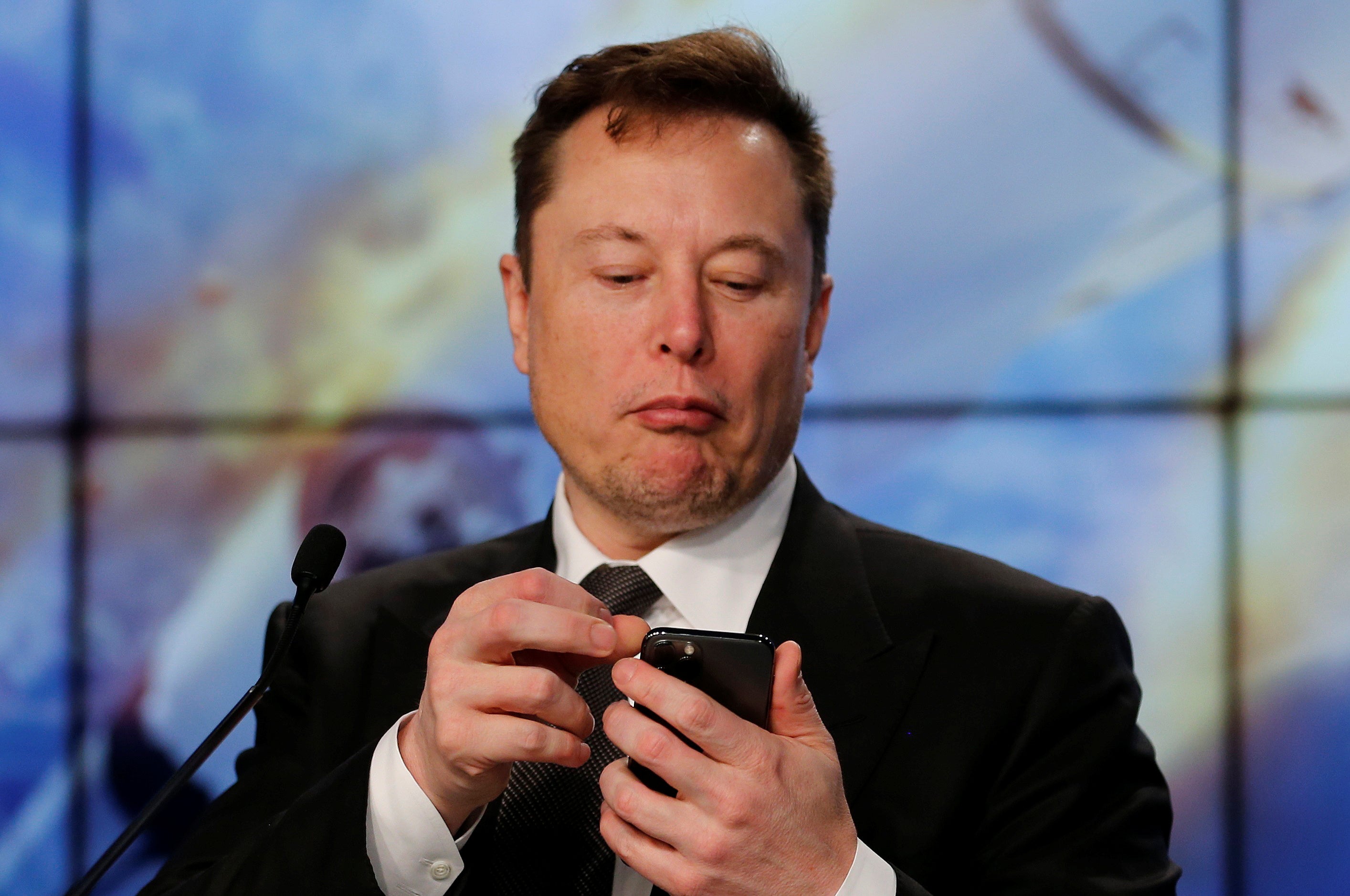 Elon Musk looks at his phone during a post-launch news conference to discuss a SpaceX Crew test. The Kremlin has not publicly responded to his request