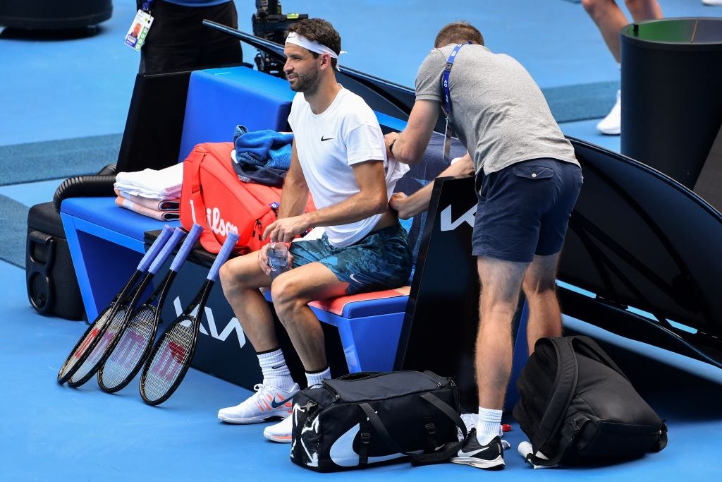 Grigor Dimitrov is treated by a trainer during his quarter-final match against Aslan Karatsev