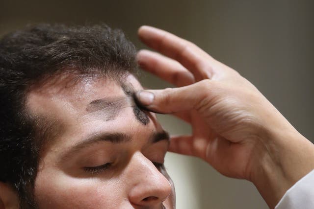 A Catholic receives ashes on his forehead while celebrating Ash Wednesday