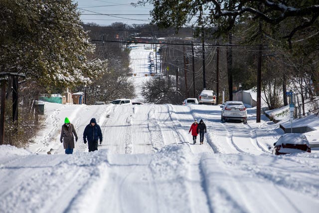 Pedestrians walk on an icy road on 15 February 2021 in East Austin, Texas. Winter storm Uri has brought historic cold weather to Texas, causing traffic delays and power outages, and storms have swept across 26 states with a mix of freezing temperatures and precipitation