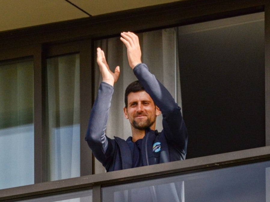 Novak Djokovic gestures from his hotel balcony
