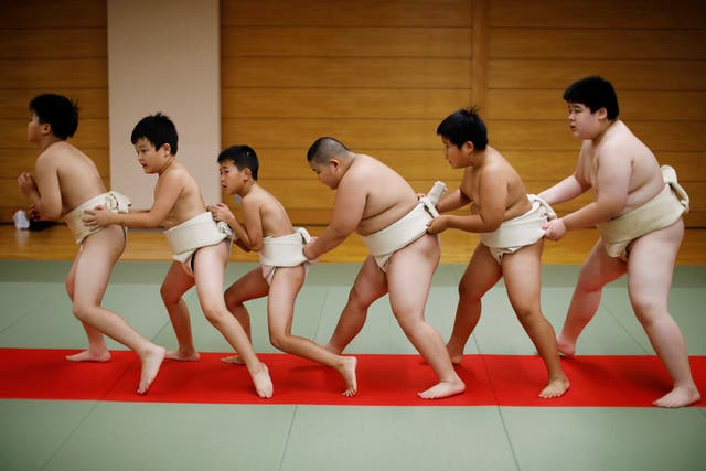 <p>Kyuta, centre, warms up with other boys before training, at Komatsuryu sumo club, Tokyo, in August of last year</p>