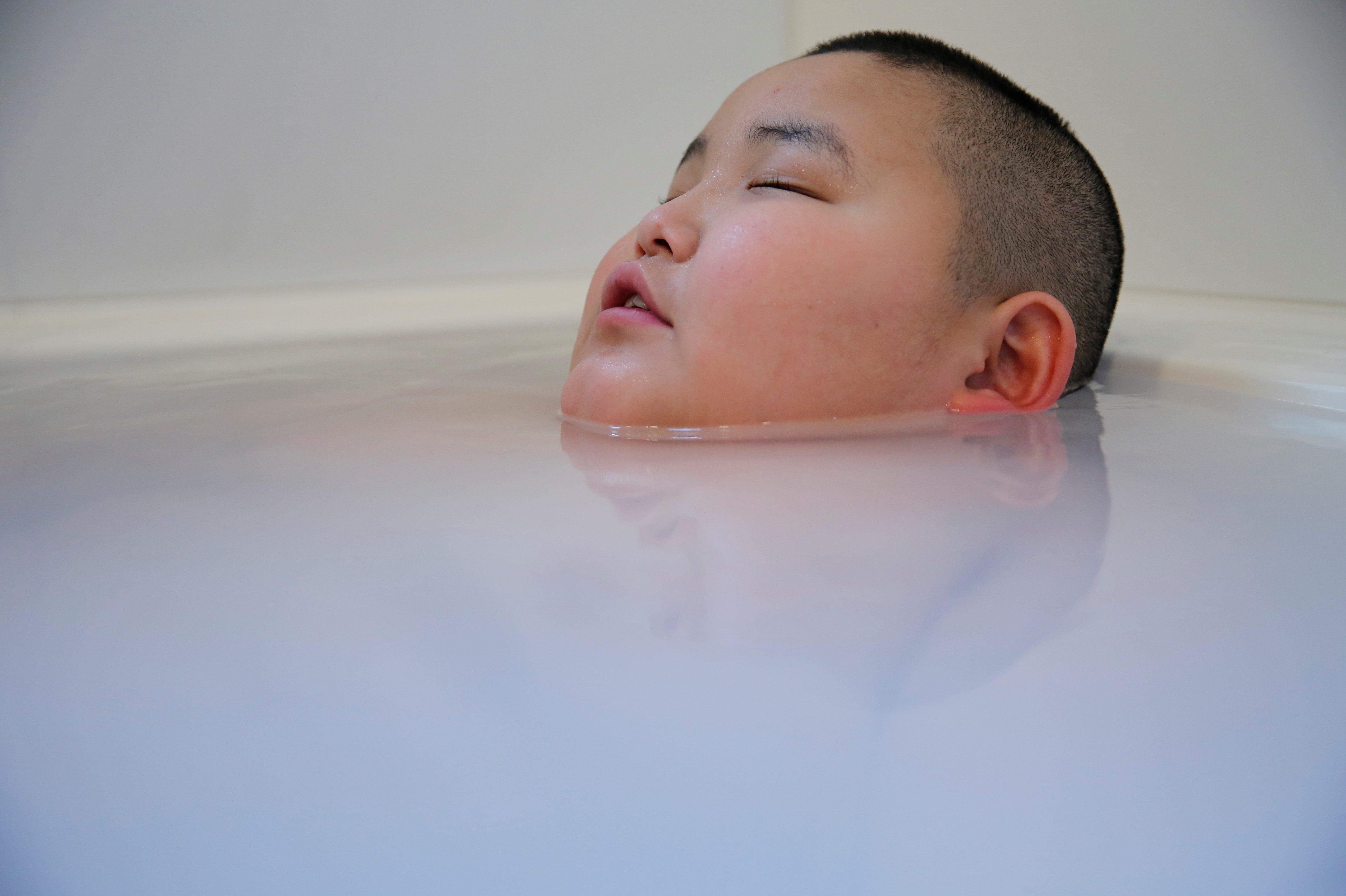 Kyuta takes a bath after coming back from school at his home in Tokyo