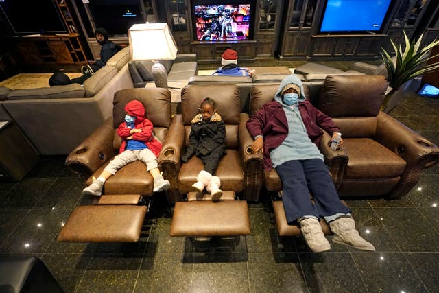 Joecyah Heath, left, Morning Day, center, and Jenesis Heath rest in recliners at a Gallery Furniture store which opened as a shelter Wednesday, Feb. 17, 2021, in Houston. Millions in Texas still had no power after a historic snowfall and single-digit temperatures created a surge of demand for electricity to warm up homes unaccustomed to such extreme lows, buckling the state's power grid and causing widespread blackouts. (AP Photo/David J. Phillip)