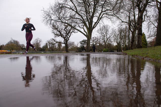 A runner is reflected in a puddle after heavy rain at Cannon Hill Park in Birmingham. 