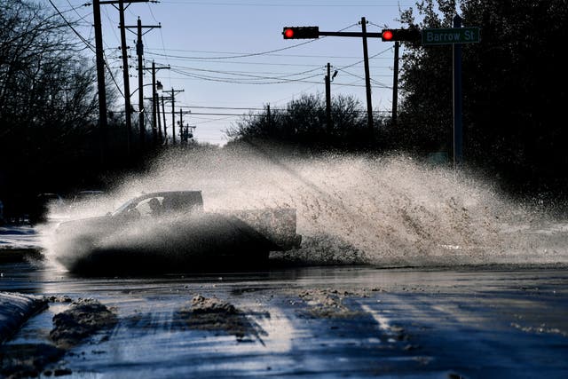A pickup sends a wake of snow melt high into the air as the driver plows through a large puddle at Barrow and South 11th streets intersection in Abilene, Texas
