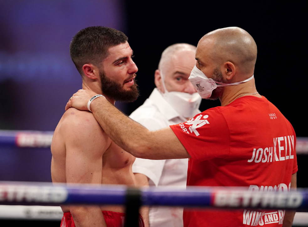 <p>Josh Kelly is comforted by trainer Adam Booth</p>