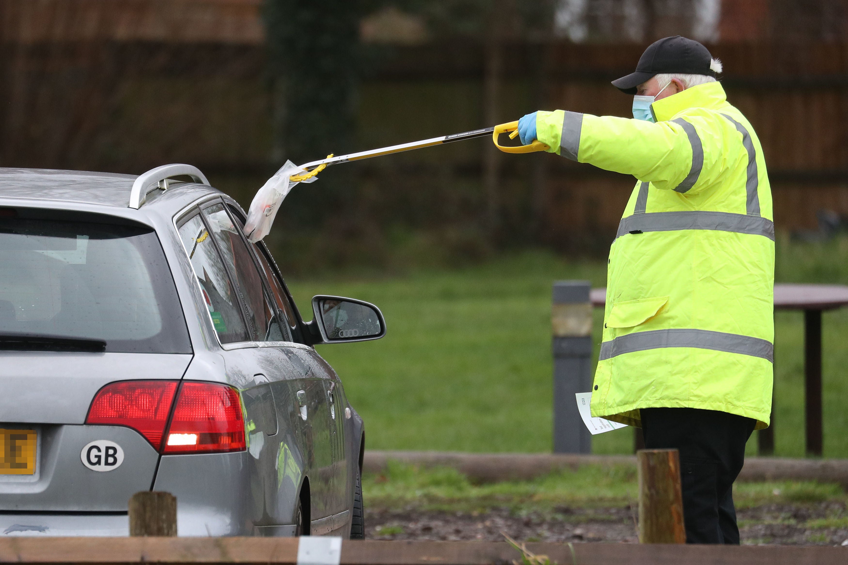 A test and trace worker in the Bramley Inn car park in Bramley, near Basingstoke, Hampshire takes a coronavirus test from a driver at a surge testing programme with local residents, after a case of the South African variant of Covid-19 was identified in the village