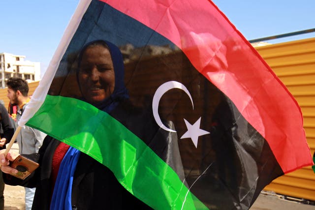 A woman waves a national flag as Libyans mark the 10th anniversary of the 2011 revolution, in the eastern city of Benghazi