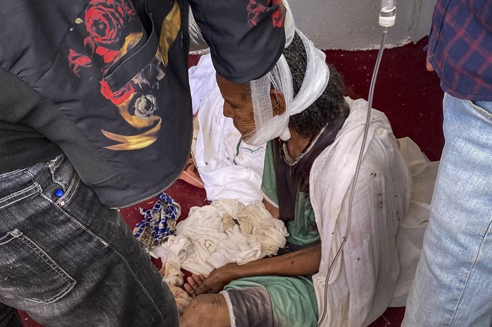 An elderly woman who fled to the city of Axum in the Tigray region of Ethiopia to seek safety sits with her head bandaged after being wounded during an attack on the city