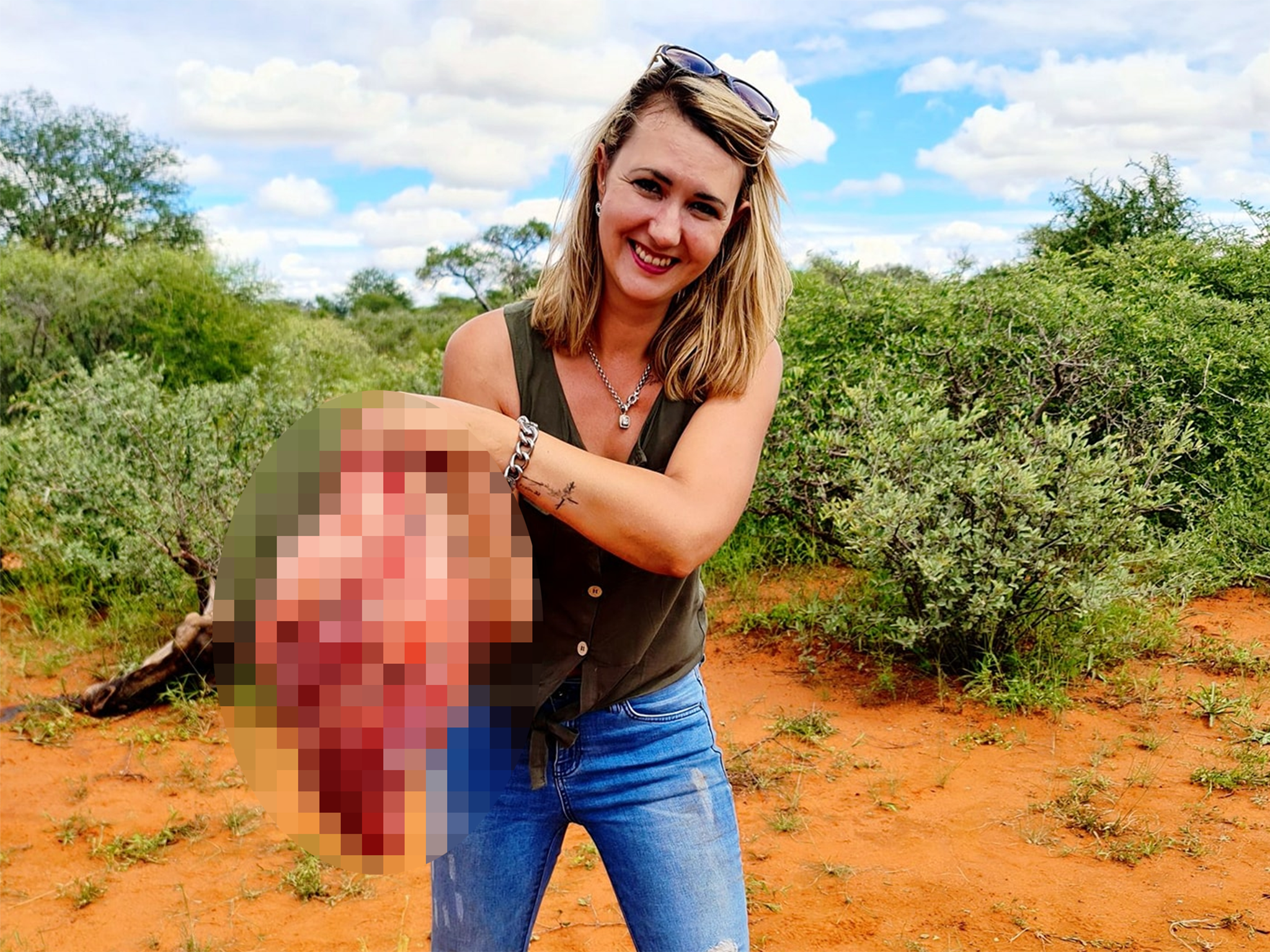 Merelize Van Der Merwe posing with the heart of a giraffe she has just killed