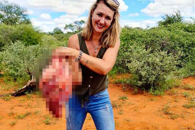 Merelize Van Der Merwe posing with the heart of a giraffe she has just killed