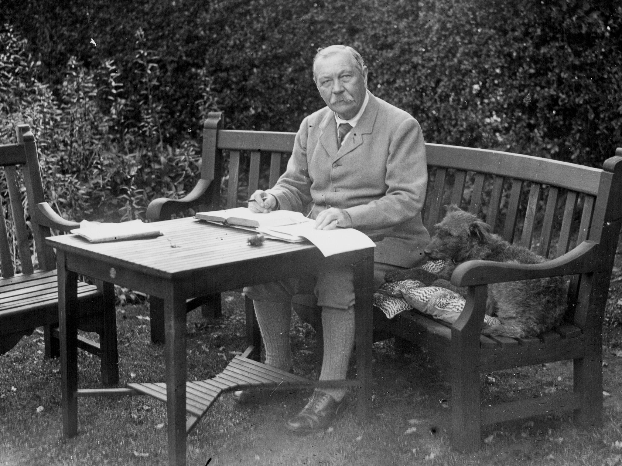 Doyle sitting at a table in his garden in Hampshire