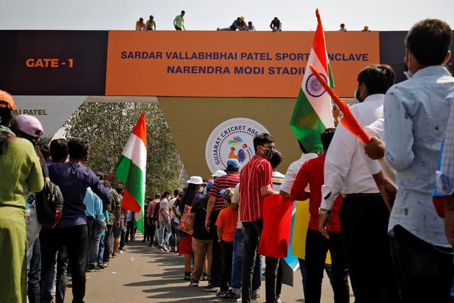 Workers install a hoarding renaming the world’s largest cricket stadium after Narendra Modi, even as fans wait to enter before the start of the third Test match between India and England