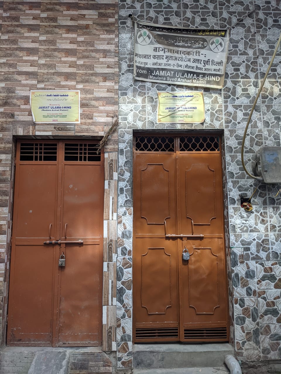 Banners of NGOs pasted above the doors of the houses which are rebuilt with their donations after they were burnt down during the violence last year