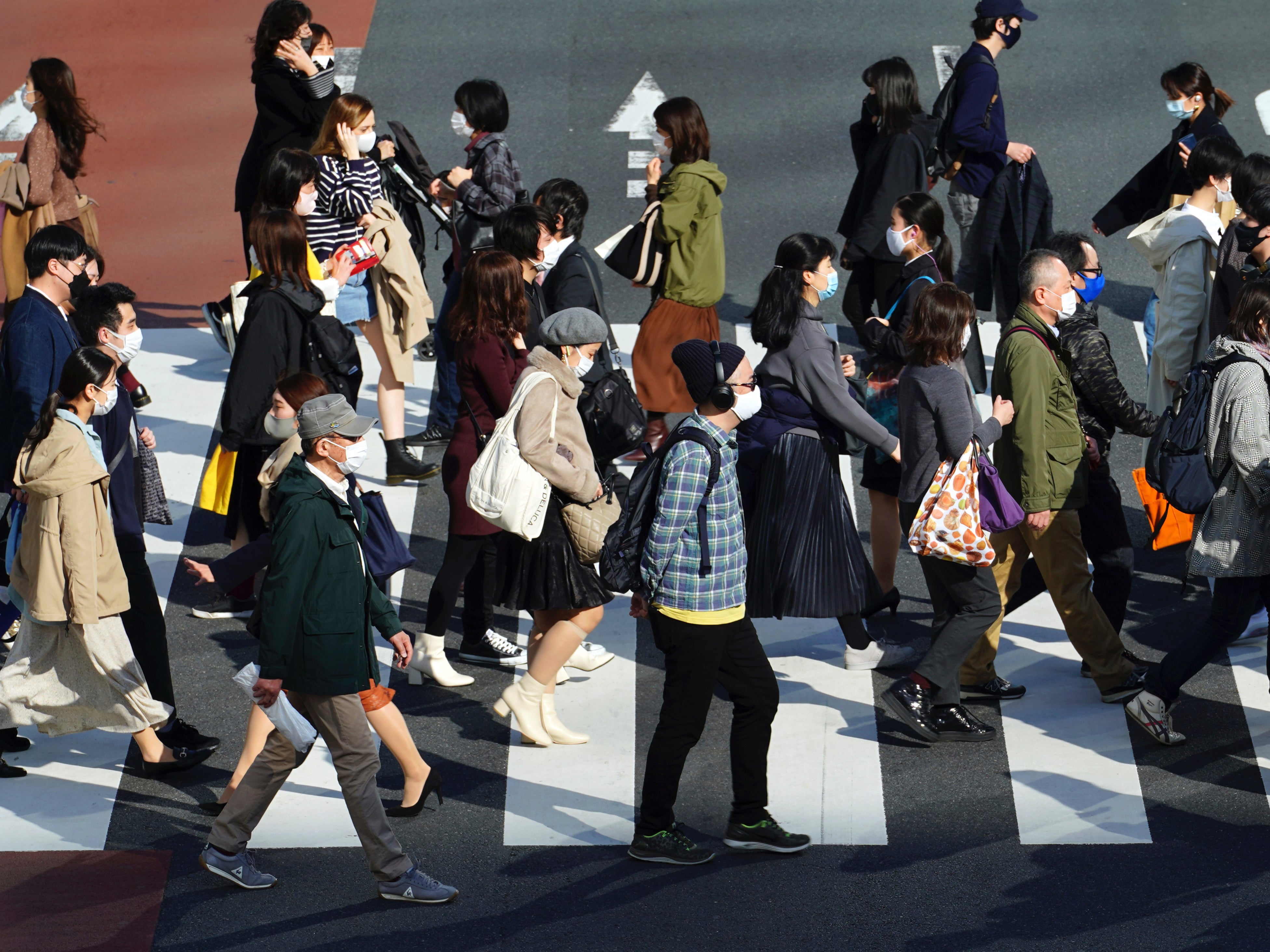 People wearing protective masks to help curb the spread of the coronavirus walk at a pedestrian crossing in Tokyo