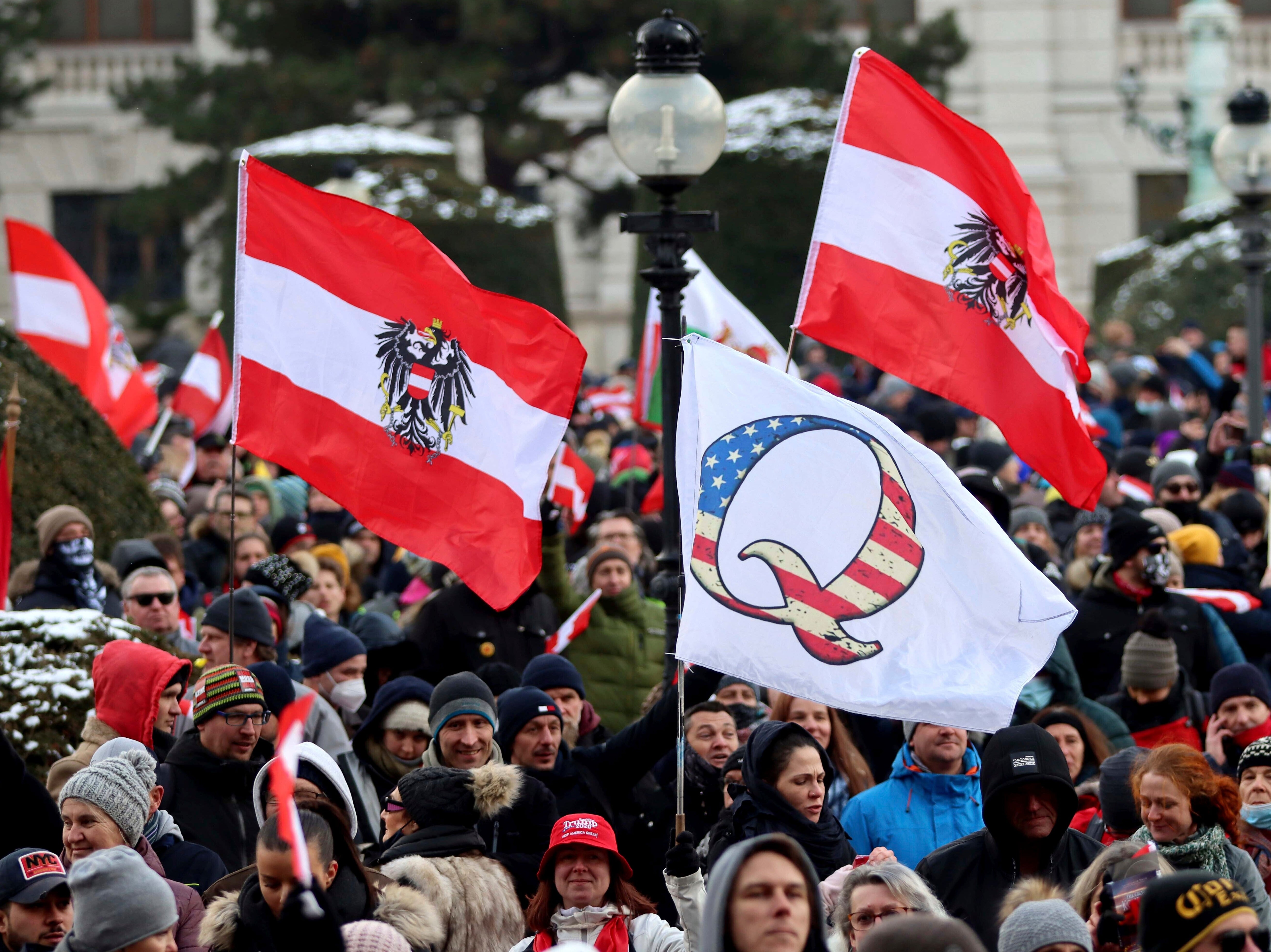 Demonstrators waves Austrian and QAnon flags during a protest against government restriction measures to curb the spread of Covid-19 in Vienna, Austria, on Saturday 16 January 2021