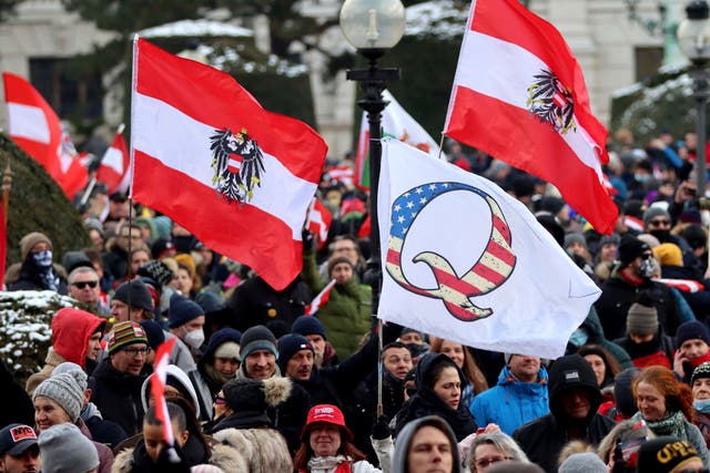 Demonstrators waves Austrian and QAnon flags during a protest against government restriction measures to curb the spread of Covid-19 in Vienna, Austria, on Saturday 16 January 2021