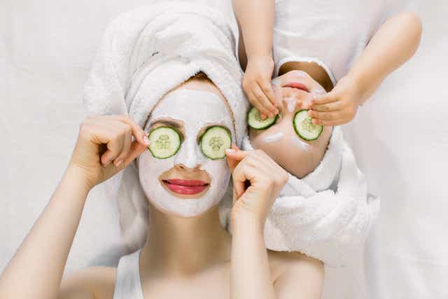 mother and daughter with facial masks on and cucumbers on their eyes