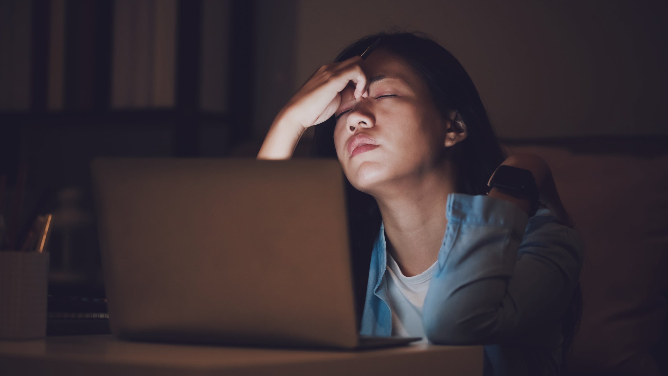 exhausted woman in front of a laptop at night