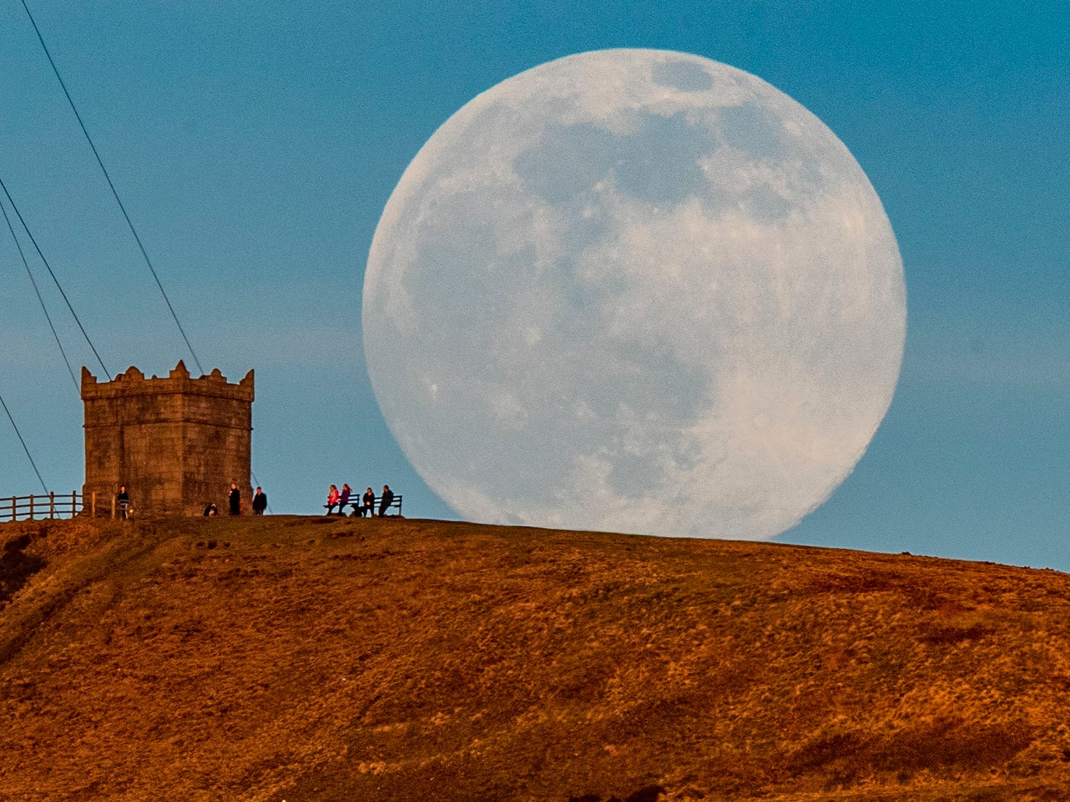 The snow moon rises behind Rivington Pike near Bolton, Greater Manchester.