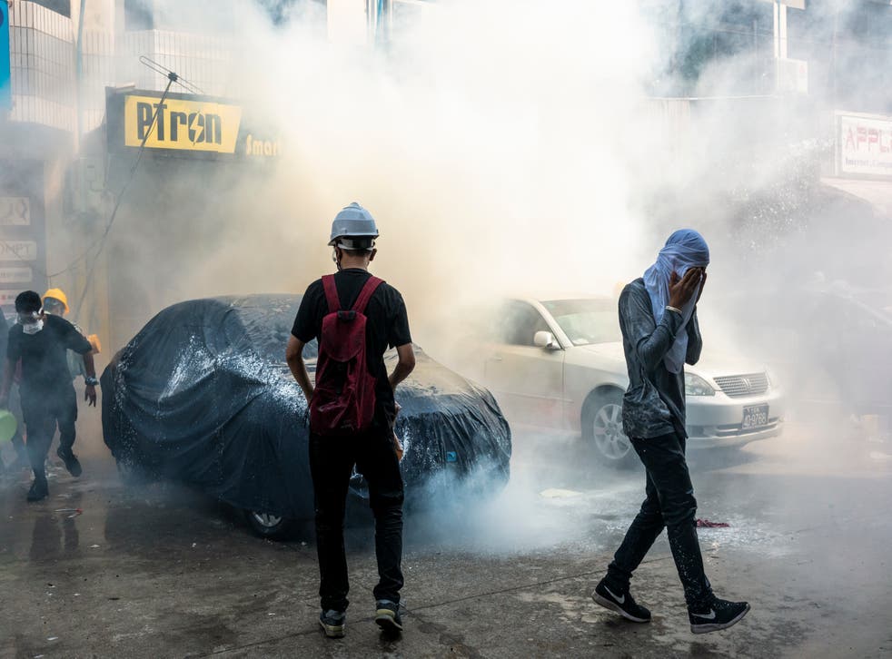  Protesters attempt to put out a tear gas canister fired by riot police