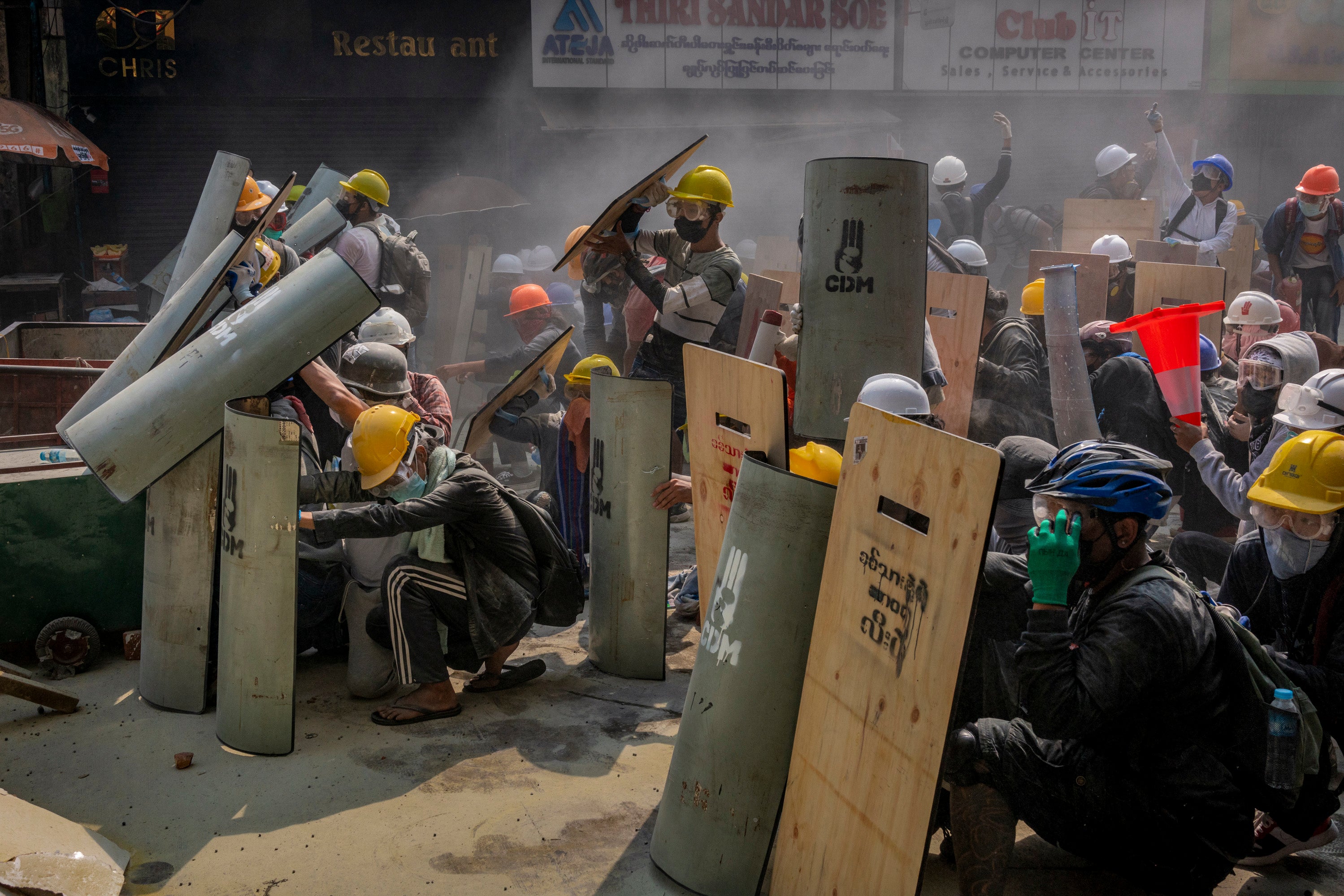 Protesters defend themselves with makeshift shields during clashes with riot police in Yangon