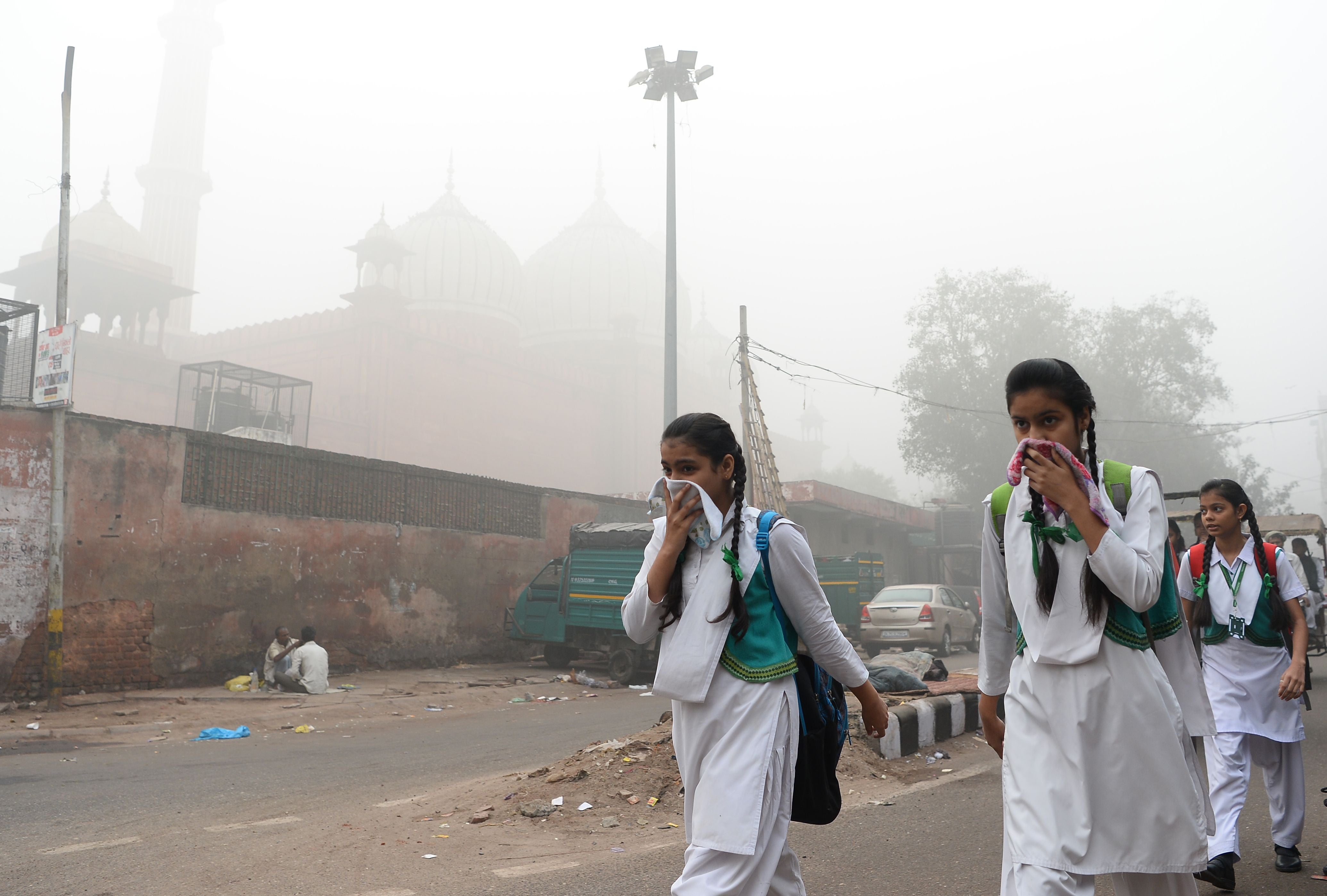 Indian schoolchildren shield their faces from heavy smog in New Delhi