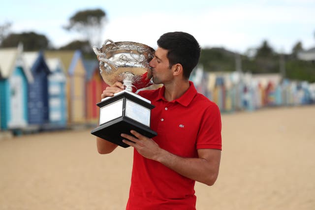 Novak Djokovic celebrates with the Australian Open trophy on Brighton Beach in Melbourne