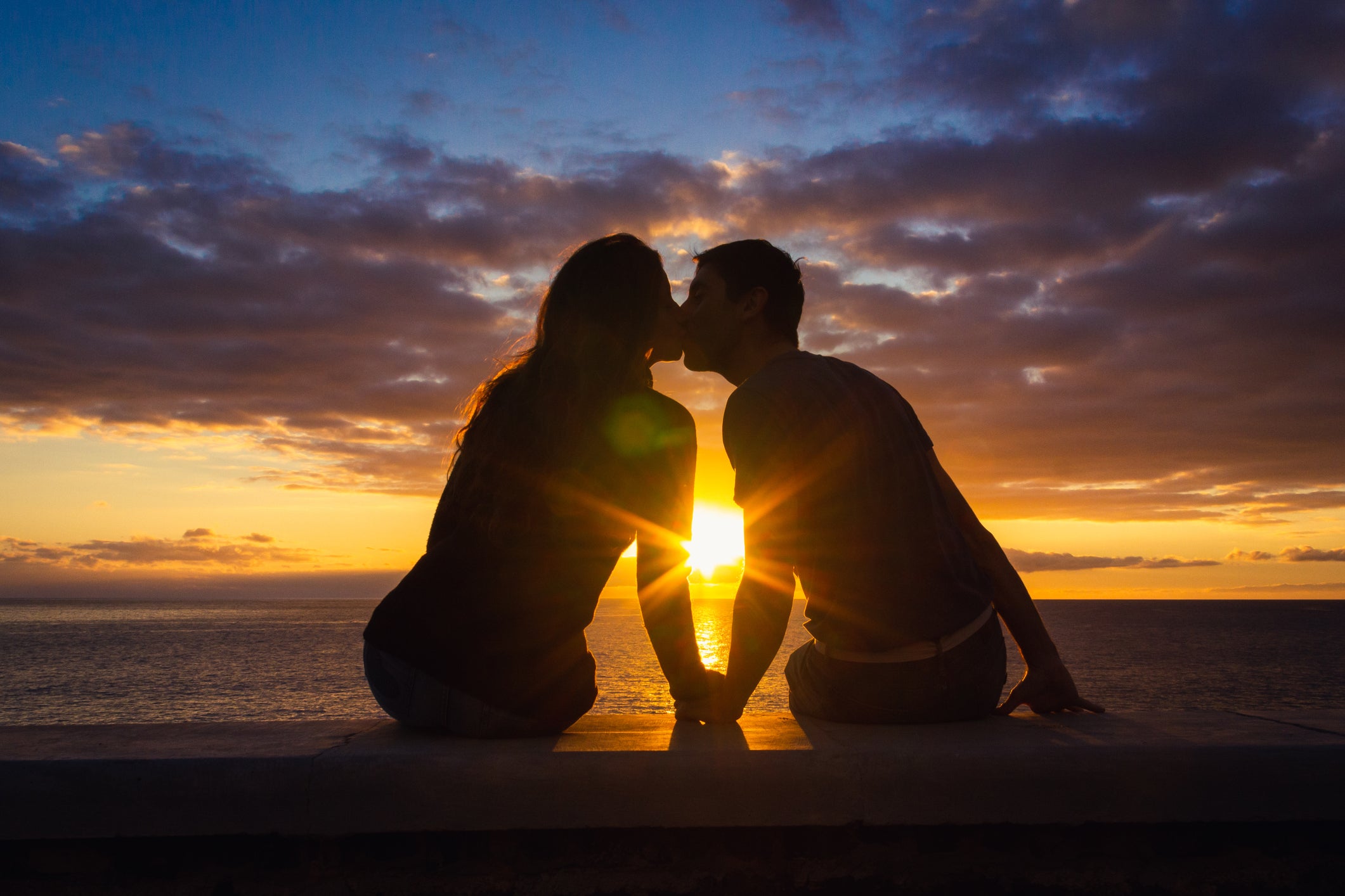 couple kissing in front of a sunset