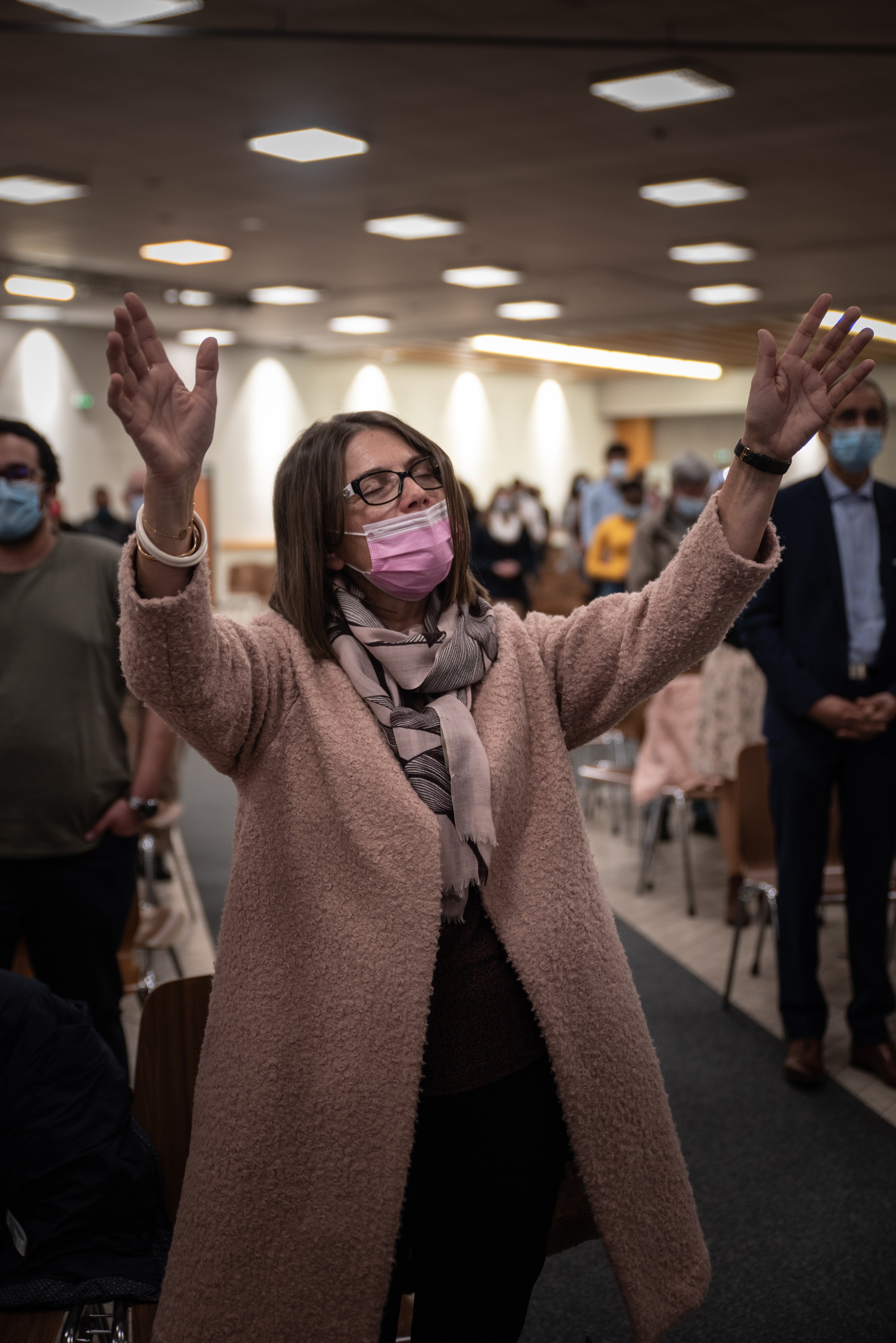 A woman raises her hands in prayer during the service